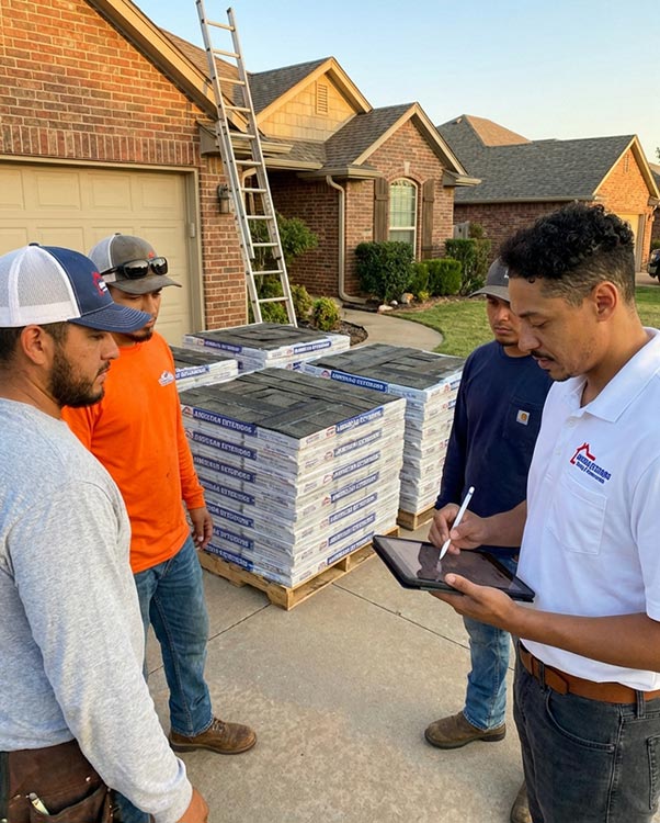 American Exteriors team consulting with homeowners at residential roof replacement site with premium roofing materials